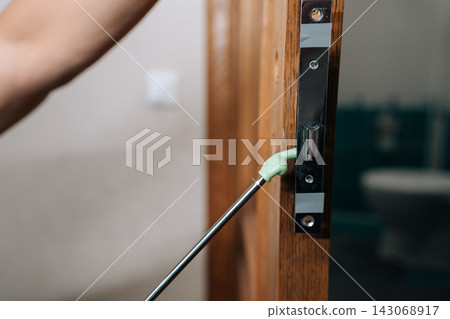 Close-up of unrecognizable person learning and performing door lock and handle replacement, using telescopic pointer for detailed instruction during home improvement training session. Close-up of unrecognizable person learning and performing door lock and handle replacement, using telescopic pointer for detailed instruction during home improvement training session. 143068917