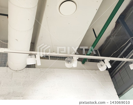 Industrial ceiling with track lighting and ventilation system in modern workspace environment Industrial ceiling with track lighting and ventilation system in modern workspace environment 143069010