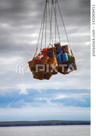 Helicopter carries sling (rope mesh) with empty metal barrels 143069451