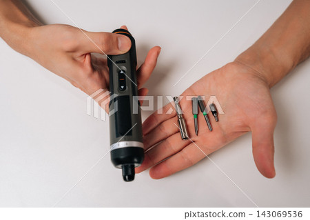 Top view of person holding precision cordless electric screwdriver tool kit, presenting various bits for electronics and home repair, modern technology and practical solutions for diy projects. Top view of person holding precision cordless electric screwdriver tool kit, presenting various bits for electronics and home repair, modern technology and practical solutions for diy projects. 143069536