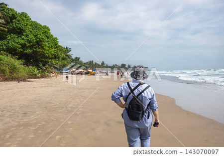 Arambol Beach with palm trees, beach umbrellas and people walking on the sandy beach Arambol Beach with palm trees, beach umbrellas and people walking on the sandy beach 143070097