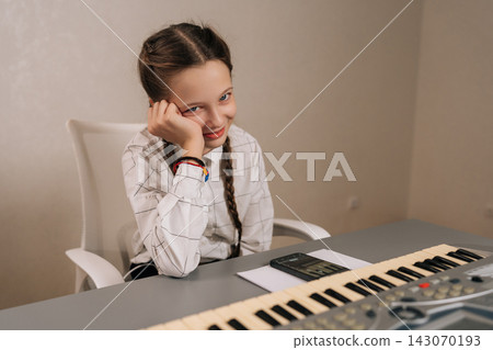 Pensive smiling young girl resting head on hand at digital piano, bored and weary during music lesson, needing a break from intense practice and concentration. Pensive smiling young girl resting head on hand at digital piano, bored and weary during music lesson, needing a break from intense practice and concentration. 143070193