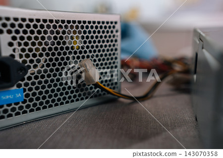 Computer power supply unit distributing electricity to components, showing its ventilation grid, ac in puta connected wire ready for installation or repair. Computer power supply unit distributing electricity to components, showing its ventilation grid, ac in puta connected wire ready for installation or repair. 143070358