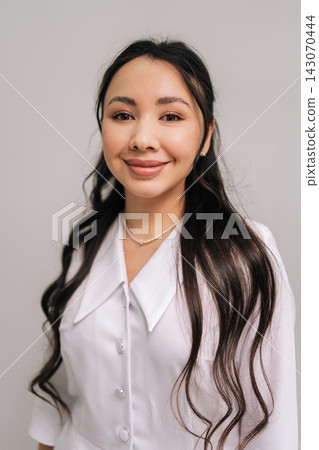 Cheerful Asian woman beautician standing in white uniform, representing confident and professional cosmetologist or doctor offering beauty and aesthetic services in modern medical clinic. Cheerful Asian woman beautician standing in white uniform, representing confident and professional cosmetologist or doctor offering beauty and aesthetic services in modern medical clinic. 143070444