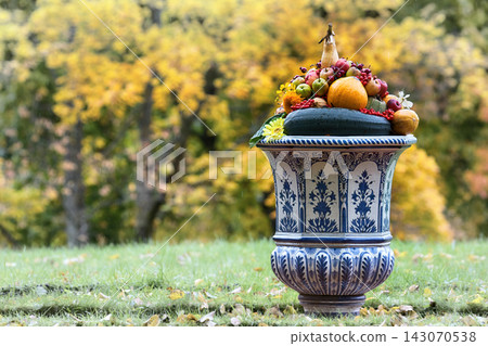 Still life of vegetables, flowers, yellow leaves, fruits in large vase Still life of vegetables, flowers, yellow leaves, fruits in large vase 143070538