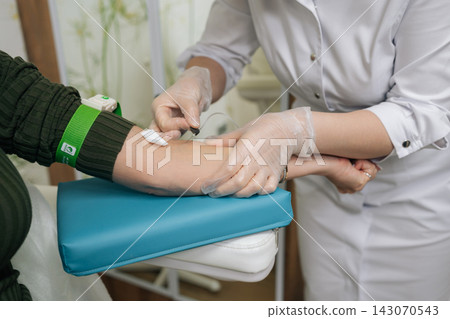 Nurse performing blood draw from patient arm, collecting sample for diagnostic testing, illustrating routine health check-ups and laboratory analysis in modern clinic. Concept of healthy lifestyle. Nurse performing blood draw from patient arm, collecting sample for diagnostic testing, illustrating routine health check-ups and laboratory analysis in modern clinic. Concept of healthy lifestyle. 143070543