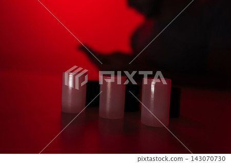 Photographer working in darkroom, preparing 35mm film canisters for analog development under controlling red light, focusing on traditional process of creating images, close-up. Photographer working in darkroom, preparing 35mm film canisters for analog development under controlling red light, focusing on traditional process of creating images, close-up. 143070730