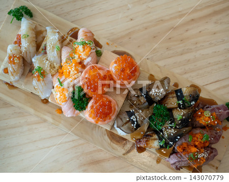 Top view of big meal with assorted and various sushi on a wooden tray in japanese restaurant. Japanese food. Top view of big meal with assorted and various sushi on a wooden tray in japanese restaurant. Japanese food. 143070779