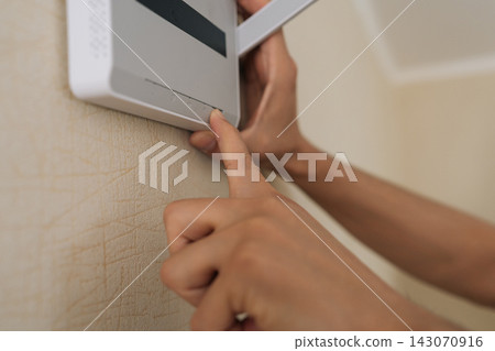 Close-up shot showing person finger pressing button on white wireless router mounted on wall. Shallow depth of field focuses on technology connectivity. Neutral colors create modern, everyday feel. 143070916