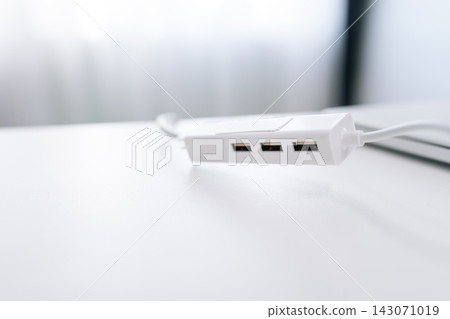 Close-up of modern white USB hub splitter on minimalist desk. Bright, high key lighting with shallow depth of field. Clean technology concept for office, workspace, or connectivity. Close-up of modern white USB hub splitter on minimalist desk. Bright, high key lighting with shallow depth of field. Clean technology concept for office, workspace, or connectivity. 143071019