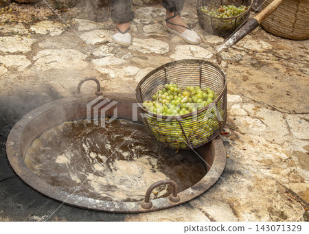 Green grapes being lifted from a copper cauldron during traditional L'Escalda raisin activity in a local setting Green grapes being lifted from a copper cauldron during traditional L'Escalda raisin activity in a local setting 143071329