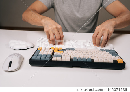 Close-up of man placing cloud-shaped wrist rest for ergonomic comfort while using mechanical keyboard and wireless mouse on clean white desk, highlighting modern desk setup for work or gaming. Close-up of man placing cloud-shaped wrist rest for ergonomic comfort while using mechanical keyboard and wireless mouse on clean white desk, highlighting modern desk setup for work or gaming. 143071386