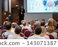 Conference presentation with a handshake image on screen 143071387