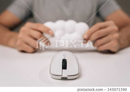 Selective focus of man holding wrist pad for computer mouse, providing ergonomic support and comfort working on home office desk, preventing carpal tunnel syndrome and repetitive strain injury. Selective focus of man holding wrist pad for computer mouse, providing ergonomic support and comfort working on home office desk, preventing carpal tunnel syndrome and repetitive strain injury. 143071390