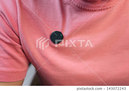 Professional journalist preparing for recording session by placing small, modern wireless lavalier microphone onto pink shirt using a magnetic clip for optimal sound quality. Professional journalist preparing for recording session by placing small, modern wireless lavalier microphone onto pink shirt using a magnetic clip for optimal sound quality. 143072243