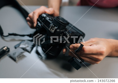 Close-up view of content creator hands setting up and synchronizing wireless lapel microphone system, connecting receiver to digital camera for professional audio recording. Close-up view of content creator hands setting up and synchronizing wireless lapel microphone system, connecting receiver to digital camera for professional audio recording. 143072266
