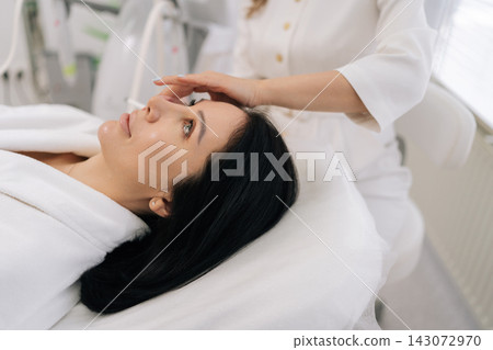 Closeup shot of cosmetologist performing microneedling with mesotherapy serum on woman face in professional clinic, promoting collagen, skin rejuvenation, lifting and glowing anti-aging results. Closeup shot of cosmetologist performing microneedling with mesotherapy serum on woman face in professional clinic, promoting collagen, skin rejuvenation, lifting and glowing anti-aging results. 143072970