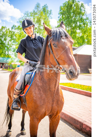 Lovely young woman wearing helmet riding her brown horse Lovely young woman wearing helmet riding her brown horse 143073094