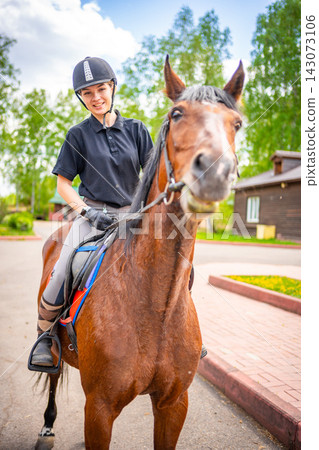 Lovely young woman wearing helmet riding her brown horse Lovely young woman wearing helmet riding her brown horse 143073106