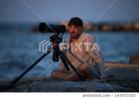 Man takes photos by the seaside at dusk Man takes photos by the seaside at dusk 143073583