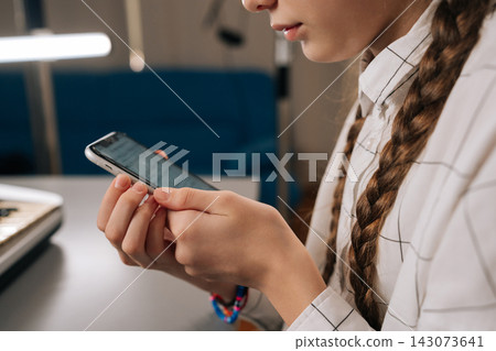 Close-up of young girl using smartphone displaying sheet music, using digital device for learning piano while sitting at electronic keyboard, combining modern tech with musical practice. Close-up of young girl using smartphone displaying sheet music, using digital device for learning piano while sitting at electronic keyboard, combining modern tech with musical practice. 143073641
