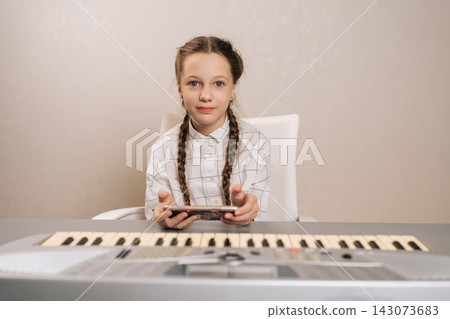 Young girl with pigtails sitting at electronic piano, focused on smartphone instead of music practice, illustrating modern screen time distraction during a home lesson. Young girl with pigtails sitting at electronic piano, focused on smartphone instead of music practice, illustrating modern screen time distraction during a home lesson. 143073683