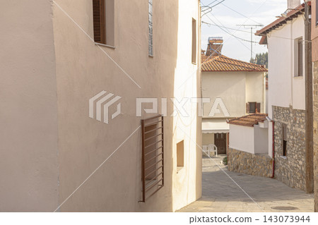 Narrow mediterranean village alleyway with stone walls and white buildings Narrow mediterranean village alleyway with stone walls and white buildings 143073944