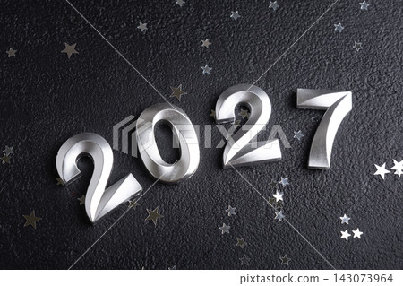 New Year 2027 celebration numbers with small silver stars on dark background New Year 2027 celebration numbers with small silver stars on dark background 143073964