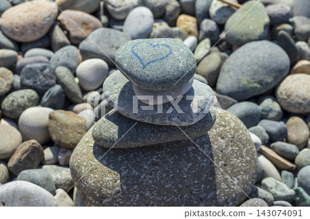 A balanced stack of zen stones on a pebble beach with a hand-drawn blue heart symbol. Concept A balanced stack of zen stones on a pebble beach with a hand-drawn blue heart symbol. Concept 143074091