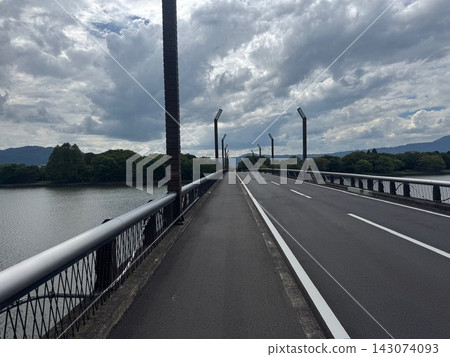 A bridge and road stretching straight under a cloudy sky. A bridge and road stretching straight under a cloudy sky. 143074093