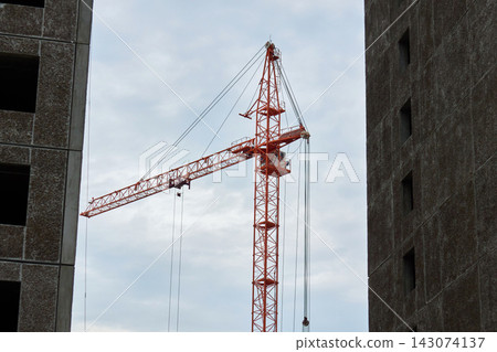 Orange Tower Crane Standing Between Concrete Panel Buildings Orange Tower Crane Standing Between Concrete Panel Buildings 143074137