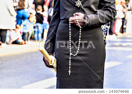 A woman dressed in traditional manola attire (with a black mantilla), holding a rosary and a large candle during a Holy Week procession in Granada, Andalusia, Spain. A woman dressed in traditional manola attire (with a black mantilla), holding a rosary and a large candle during a Holy Week procession in Granada, Andalusia, Spain. 143074698