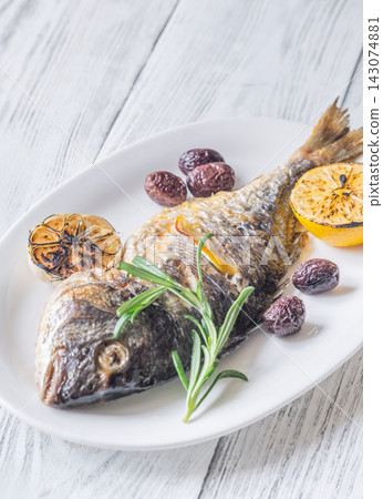 Whole roasted sea bream with lemon rosemary olives and caramelized garlic Mediterranean style Whole roasted sea bream with lemon rosemary olives and caramelized garlic Mediterranean style 143074881