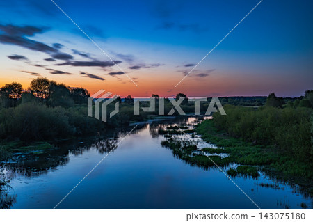Dusk Over a Calm River with Lush Greenery in the Belarusian Countryside Dusk Over a Calm River with Lush Greenery in the Belarusian Countryside 143075180