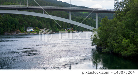 High bridge spanning fjord with forested shoreline and residential buildings, Norway High bridge spanning fjord with forested shoreline and residential buildings, Norway 143075204