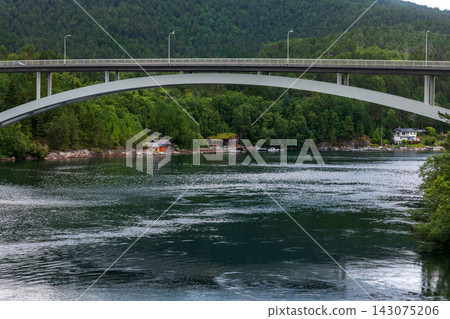 Arch bridge spanning forested river valley with residential buildings, Norway Arch bridge spanning forested river valley with residential buildings, Norway 143075206