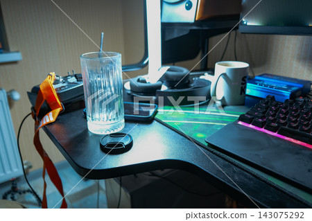Cluttered gaming desk with pink keyboard glow in Belarus home office Cluttered gaming desk with pink keyboard glow in Belarus home office 143075292
