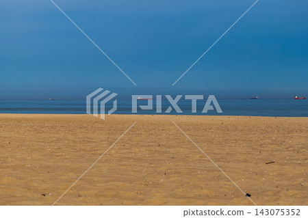 Sandy beach and distant cargo ships on Baltic Sea shore at midday Sandy beach and distant cargo ships on Baltic Sea shore at midday 143075352