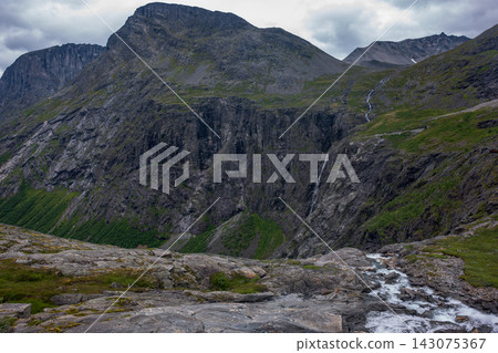 Mountain valley with basalt cliffs, alpine stream, and cascading waterfall, Norway 143075367