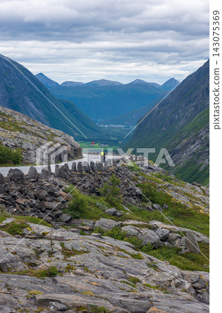 Cyclist on mountain pass road overlooking glacial valley, Norway Cyclist on mountain pass road overlooking glacial valley, Norway 143075369
