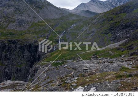 Alpine valley with cascading stream, moss-covered slopes and scree field, Norway Alpine valley with cascading stream, moss-covered slopes and scree field, Norway 143075395