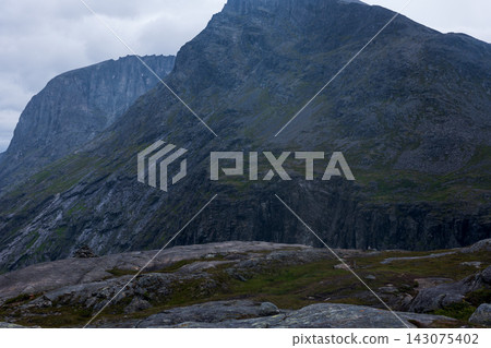 Mountain cliff face with columnar basalt formations and alpine meadow, Norway Mountain cliff face with columnar basalt formations and alpine meadow, Norway 143075402