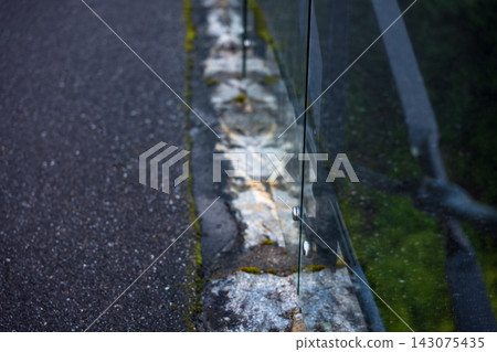 Close-up view of weathered stone barrier with moss and asphalt road, Norway Close-up view of weathered stone barrier with moss and asphalt road, Norway 143075435