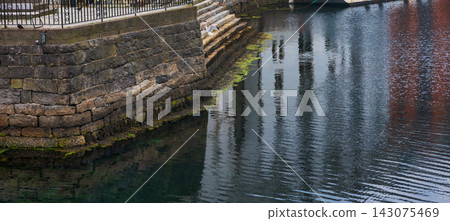 Stone harbor wall with moss growth and water reflections, Norway Stone harbor wall with moss growth and water reflections, Norway 143075469