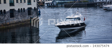 Moored motor yacht in Norwegian harbor with stone waterfront building Moored motor yacht in Norwegian harbor with stone waterfront building 143075474