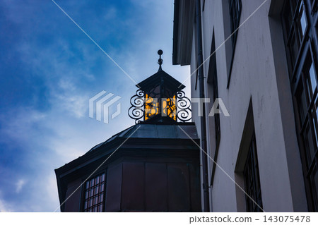 Ornamental lantern on dark wooden cupola against blue sky, Norway Ornamental lantern on dark wooden cupola against blue sky, Norway 143075478