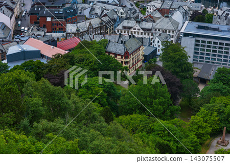 Aerial view of Norwegian town with forest and historic architecture, dense tree canopy and residential buildings Aerial view of Norwegian town with forest and historic architecture, dense tree canopy and residential buildings 143075507