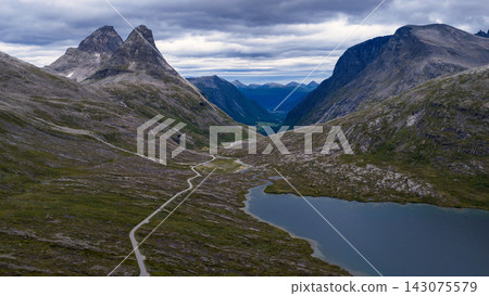 Aerial view of mountain valley with winding road and alpine lake, Rauma Norway Aerial view of mountain valley with winding road and alpine lake, Rauma Norway 143075579