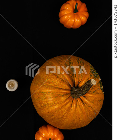 Pumpkins for Halloween on a black background with a candle nearby Pumpkins for Halloween on a black background with a candle nearby 143075843