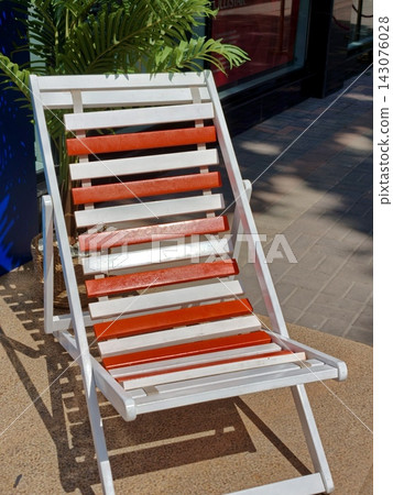 A white and red wooden deck chair outside the house. A white and red wooden deck chair outside the house. 143076028